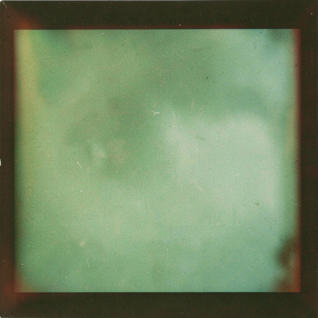 Analog film photograph of a crowd silhouette in low green-tinted light at a small venue, grainy and atmospheric