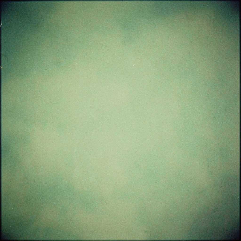 Weathered analog film photograph of a dim rehearsal room with amber stage lights glowing through haze, deep greens and warm browns, grainy and atmospheric