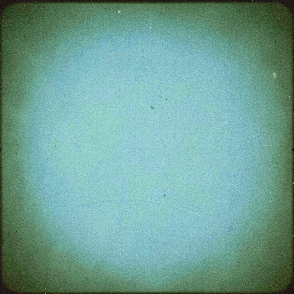 Analog film photograph of a worn electric guitar leaning in dim blue light, grainy and moody